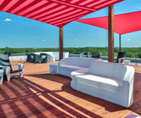 A patio with red and white furniture and a striped awning.