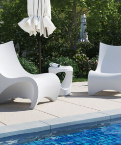 Two white lounge chairs next to a pool.